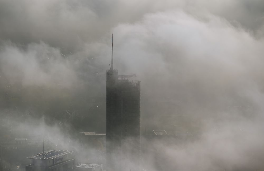 Essen aus der Vogelperspektive: Die Spitze des RWE- Turm Essen durchbricht eine imposante Nebel- und Wolkendecke über der Innenstadt im Bundesland Nordrhein-Westfalen