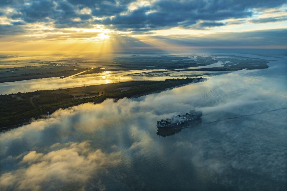 Luftaufnahme Drochtersen - Fahrendes Containerschiff in einer Nebelschicht auf dem Elbe- Flußverlauf in Drochtersen im Bundesland Niedersachsen, Deutschland