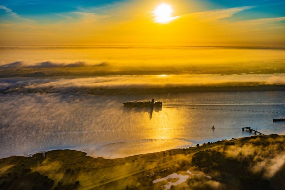 Luftaufnahme Kollmar - Fahrendes Containerschiff in einer Nebelschicht auf dem Elbe- Flußverlauf in Kolmar im Bundesland Schleswig-Holstein, Deutschland