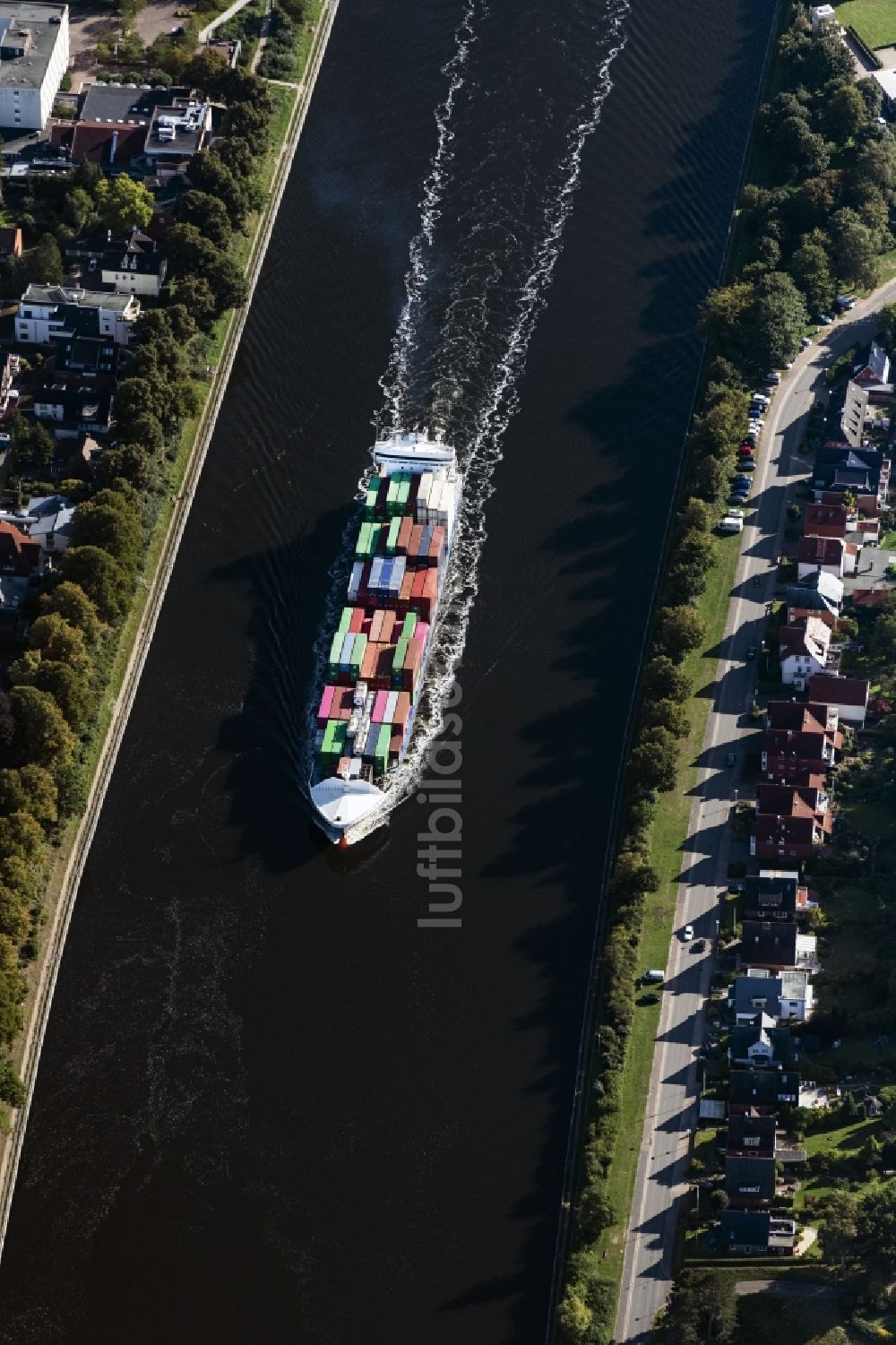 Rendsburg aus der Vogelperspektive: Fahrendes Containerschiff auf dem Nord-Ostsee-Kanal in Rendsburg im Bundesland Schleswig-Holstein, Deutschland
