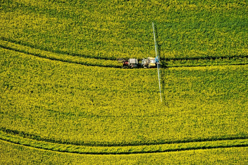 Luftaufnahme Uelde - Landmaschinen Einsatz zum Düngen von gelben Rapsfeldern in Uelde im Bundesland Nordrhein-Westfalen, Deutschland
