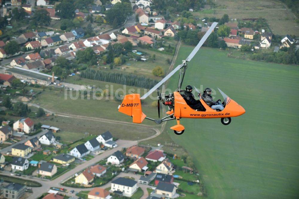 Saarmund von oben - Orange farbiger Ultraleicht - Gyrokopter der Flugschule Gyronautix mit der Kennung D-MBTF im Fluge über dem Luftraum in Saarmund im Bundesland Brandenburg