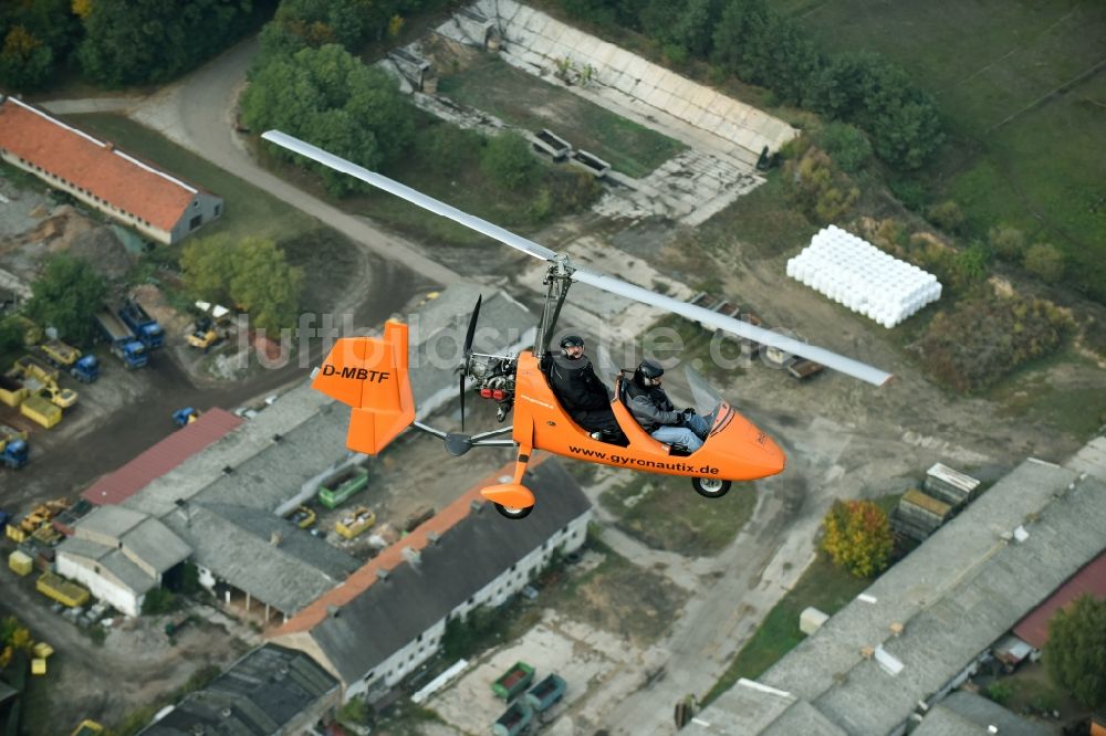 Luftaufnahme Saarmund - Orange farbiger Ultraleicht - Gyrokopter der Flugschule Gyronautix mit der Kennung D-MBTF im Fluge über dem Luftraum in Saarmund im Bundesland Brandenburg