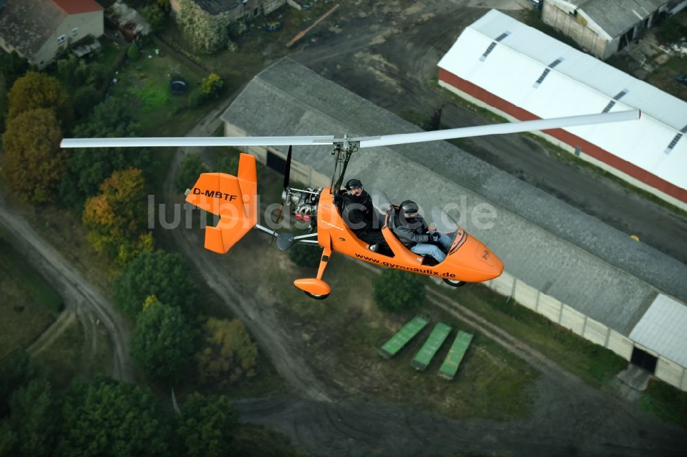 Luftaufnahme Saarmund - Orange farbiger Ultraleicht - Gyrokopter der Flugschule Gyronautix mit der Kennung D-MBTF im Fluge über dem Luftraum in Saarmund im Bundesland Brandenburg