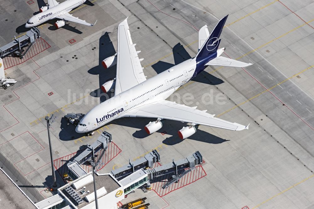 München-Flughafen aus der Vogelperspektive: Parkendes Flugzeug des Typ A380 der Lufthansa am Terminal, die aufgrund des Corona Lockdowns am Boden bleiben müssen, auf dem Gelände des Flughafen in München-Flughafen im Bundesland Bayern, Deutschland