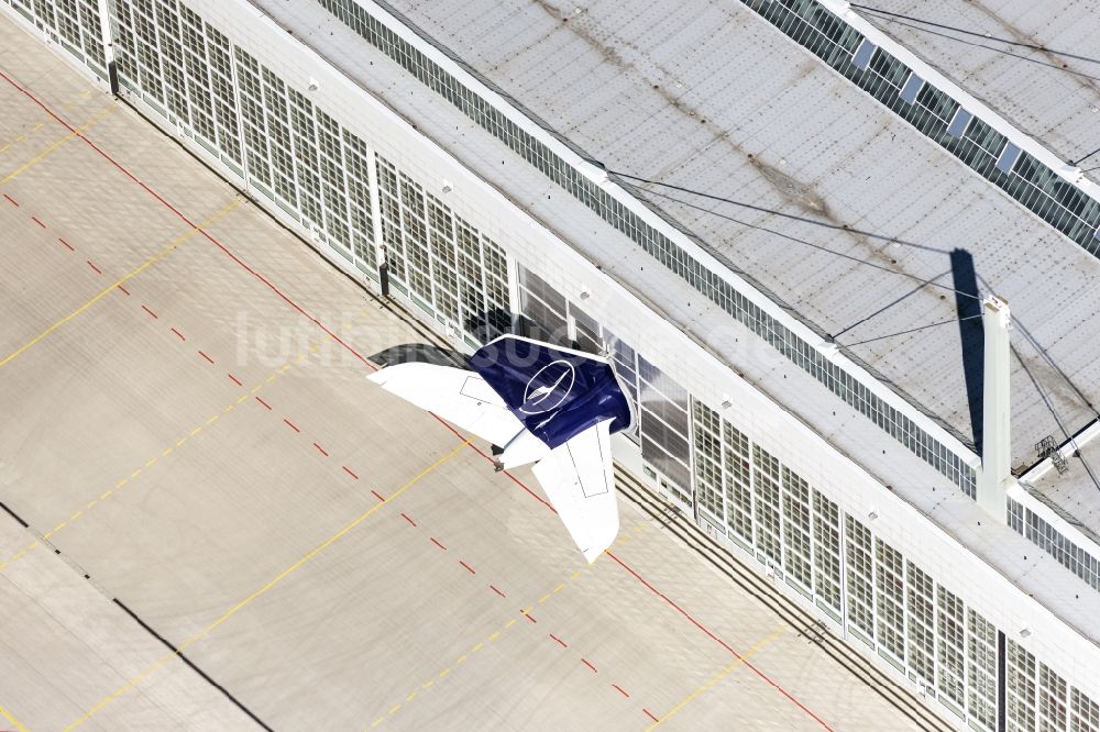 Luftbild München-Flughafen - Passagierflugzeug im Hangar abgestellt, nur das Seitenleitwerk schaut raus auf der Parkposition - Abstellfläche auf dem Flughafen in München-Flughafen im Bundesland Bayern, Deutschland