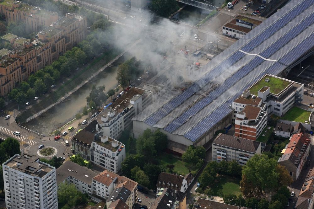 Basel aus der Vogelperspektive: Rauch- und Flammenbildung während der Löscharbeiten zum Brand in der Lagerhalle von Rhenus in Basel, Schweiz