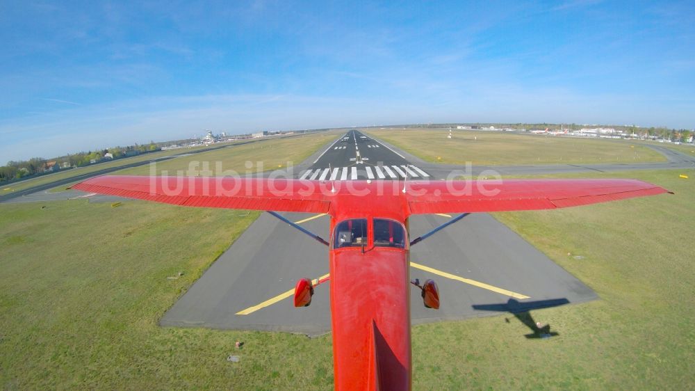 Luftaufnahme Berlin - Rote Cessna beim Tiefanflug über die Piste 26R am Flughafen Tegel in Berlin, Deutschland