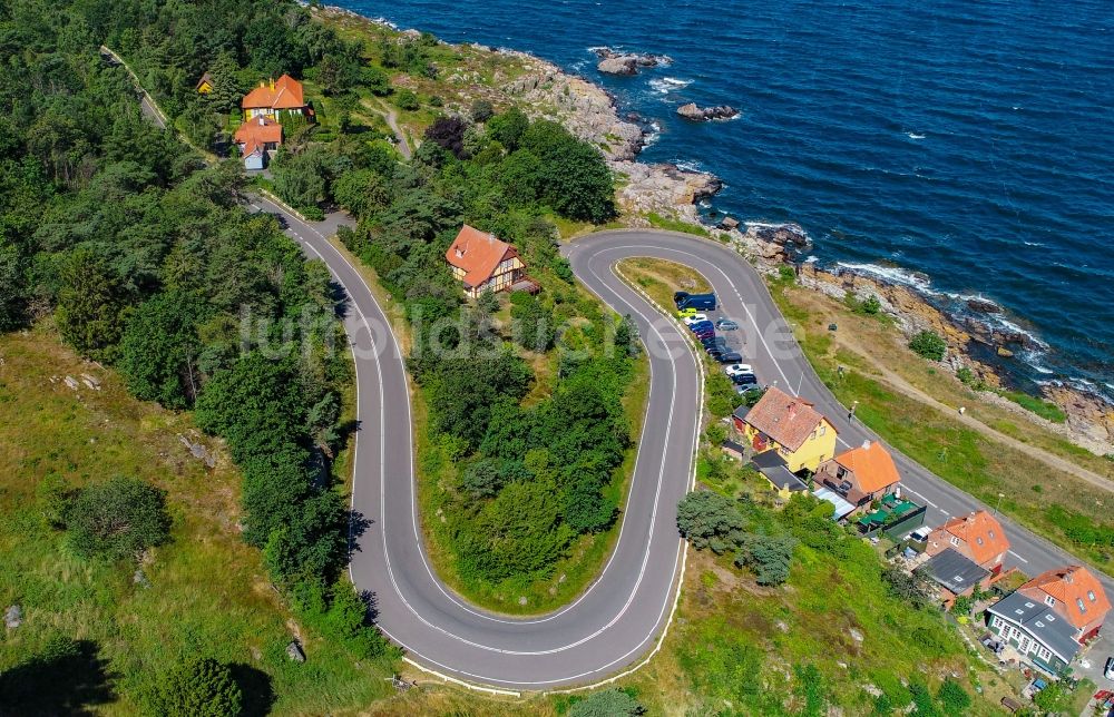 Gudhjem von oben - Serpentinenförmiger Kurvenverlauf einer Straßenführung am Ufer der Ostsee in Gudhjem in Region Hovedstaden, Dänemark