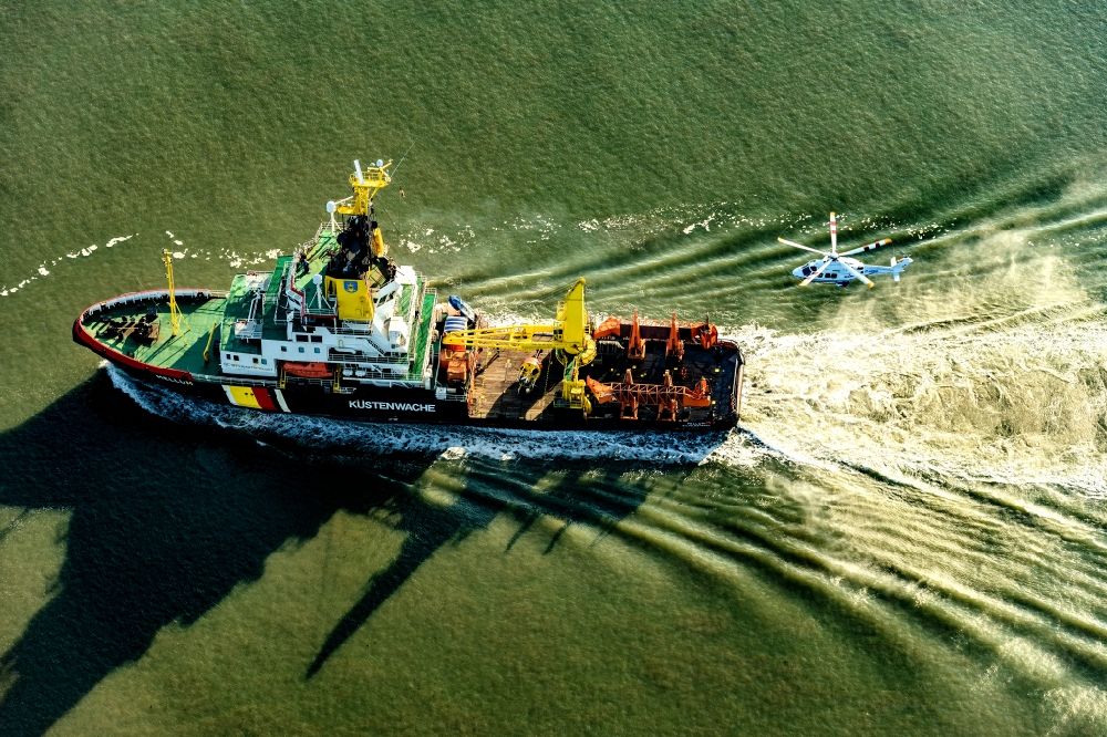 Luftbild Wilhelmshaven - Spezialschiff der Küstenwache in Fahrt bei einem Übungseinsatz mit einem Helikopter in Wilhelmshaven auf der Weser vor dem Jade Weserport im Bundesland Niedersachsen, Deutschland