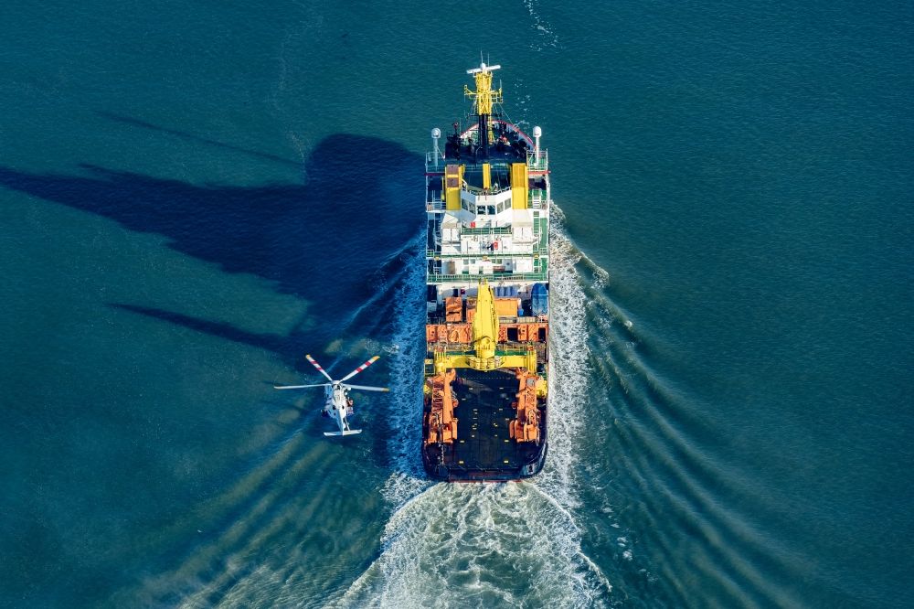 Luftaufnahme Wilhelmshaven - Spezialschiff der Küstenwache in Fahrt bei einem Übungseinsatz mit einem Helikopter in Wilhelmshaven auf der Weser vor dem Jade Weserport im Bundesland Niedersachsen, Deutschland