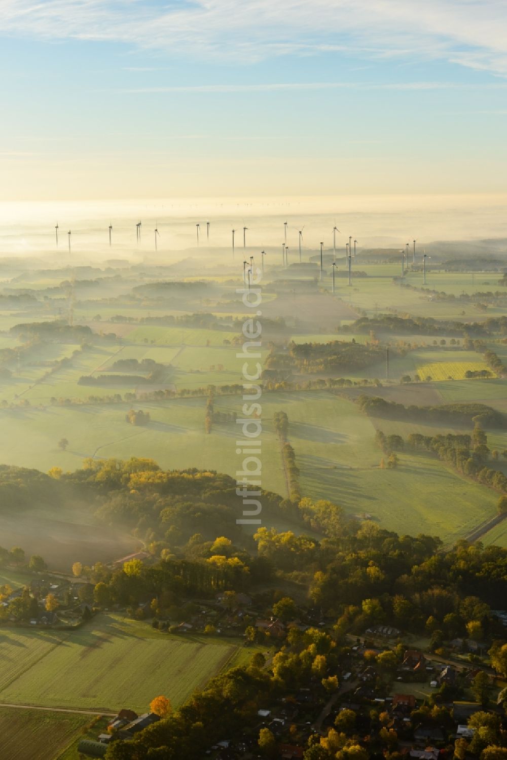 Deinste aus der Vogelperspektive: Wetterbedingt in eine Nebel- Schicht eingebettete Windenergieanlagen auf einem Feld in Deinste im Bundesland Niedersachsen, Deutschland