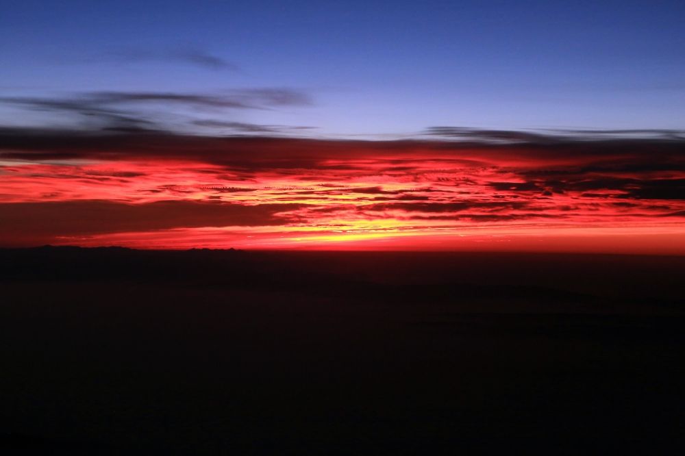 Luftaufnahme Aime - Wetterlage mit Wolkenbildung und Lichtreflektionen bei Sonnenaufgang über der Gebirgsgruppe der Seealpen in Aime in Auvergne-Rhone-Alpes, Frankreich