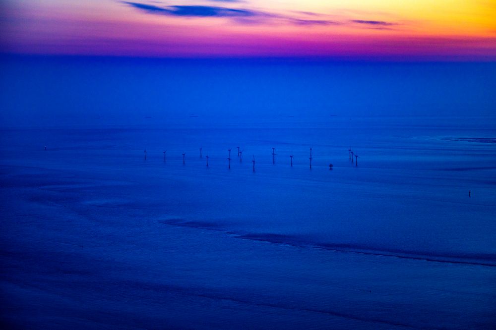 Luftaufnahme Nordergründe - Windenergieanlagen (WEA) des Offshore-Windpark bei Sonnenaufgang auf der Wasseroberfläche der Nordsee in Nordergründe im Bundesland Niedersachsen, Deutschland