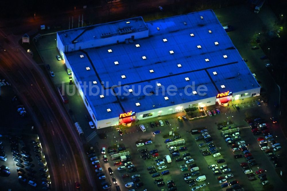 Nacht-Luftaufnahme Neuruppin - Nachtluftbild des Einkaufs- Zentrum der real GmbH in Neuruppin im Bundesland Brandenburg, Deutschland