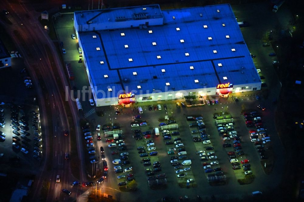 Neuruppin bei Nacht von oben - Nachtluftbild des Einkaufs- Zentrum der real GmbH in Neuruppin im Bundesland Brandenburg, Deutschland